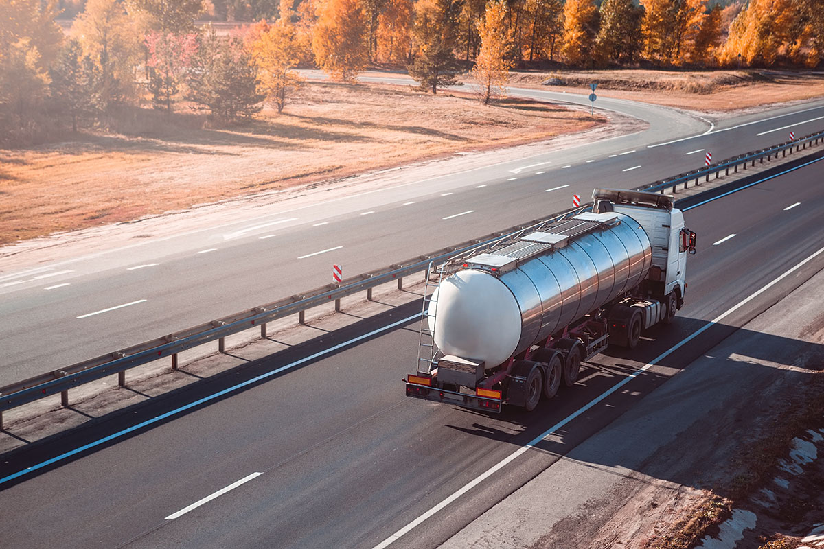 A Fields Energy road tanker on the move, seen from the side against open ground.